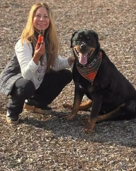 A woman crouches beside her Rottweiler, holding a small dropper bottle.