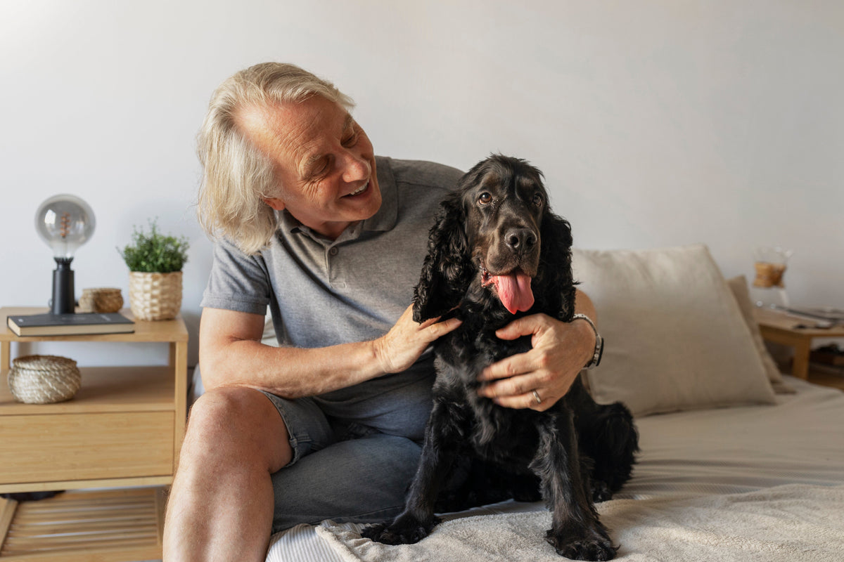 Älterer Mann streichelt seinen Hund auf dem Bett
