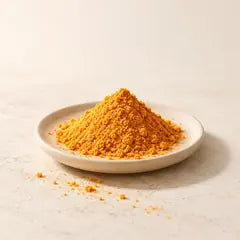 Poudre de CoQ10 orange dans une assiette ivoire.